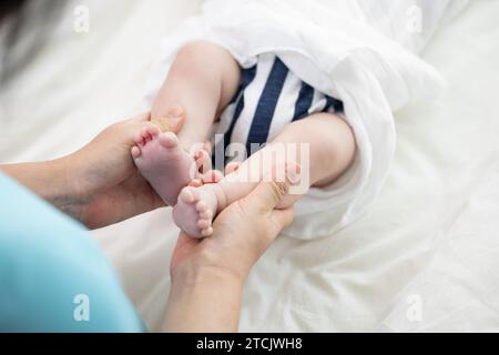 Le mani della madre massaggiano i piedi del neonato Foto Stock