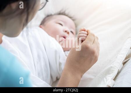 Madre che tiene la mano del neonato e gioca con lui Foto Stock