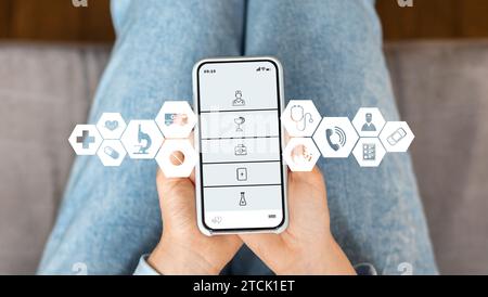 Donna a casa che utilizza un'app medica su smartphone per accedere ai servizi sanitari Foto Stock