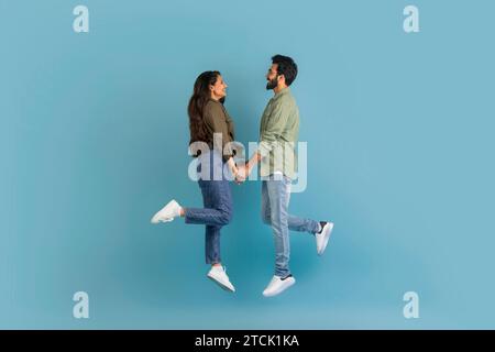 Felici amanti dell'est che si tengono per mano e saltano in alto Foto Stock