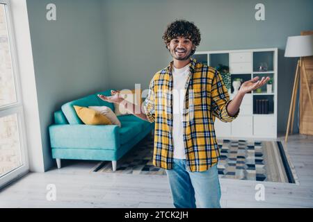 Foto di un uomo allegro e simpatico che indossa una camicia a scacchi che mostra il comfort del soggiorno in casa Foto Stock
