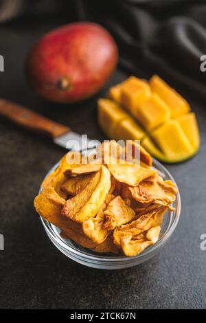Frutta secca di mango in ciotola sul tavolo nero. Foto Stock