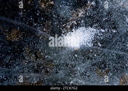 Il gruppo di bolle di metano crea forma come una cometa spaziale. Fondo di ghiaccio naturale con bolle di metano e crepe sulla superficie del lago. Lago Baikal. Foto Stock