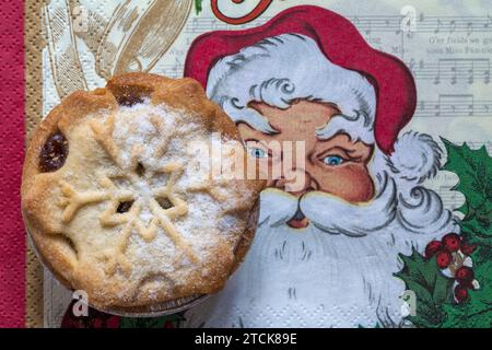 La torta mince Tesco, ricca e decadente, con pasta sfoglia al burro, è ambientata in un tovagliolo natalizio con Babbo Natale Foto Stock