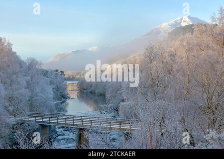 Glen Affric Cannich Scozia, prima mattina d'inverno, con nebbia sul ponte sul fiume e sulle montagne innevate Foto Stock