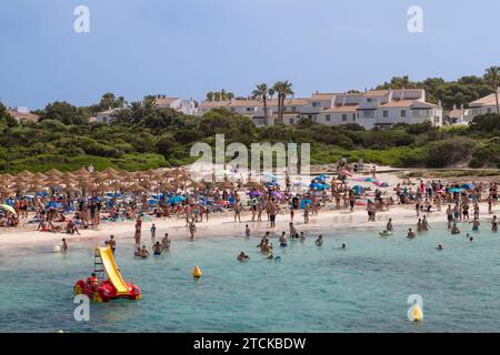 I turisti apprezzano l'acqua di mare nella località di Cala en Bosc, sull'isola spagnola di Minorca. Foto Stock