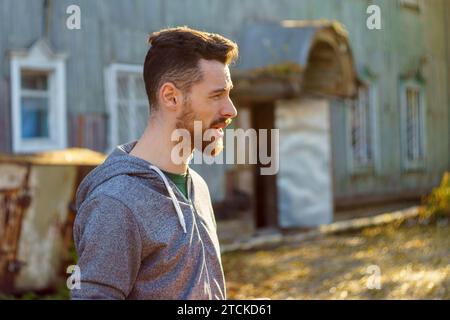 Un uomo brutale e bello, di 30-35 anni, si trova nel parco con una felpa grigia Foto Stock