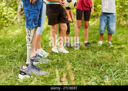 Sezione bassa di ragazzo disabile con gamba amputata in piedi con gli amici al parco Foto Stock