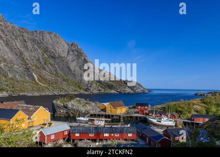 Il villaggio di pescatori di Nusfjord a Lofoten, Norvegia, presenta un pittoresco complesso di tradizionali cabine di legno rosse e gialle di Rorbu annidate ai piedi di Foto Stock