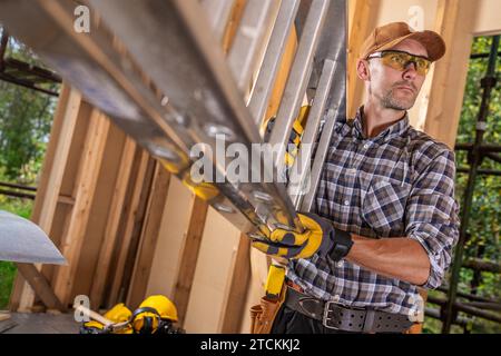 Appaltatore di cantiere caucasico nel suo operaio degli anni '40 con scala in alluminio Foto Stock