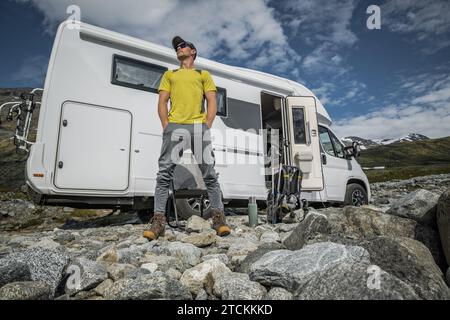 Turista caucasico nei suoi 40 anni di fronte a un camper moderno. Vacanza in un veicolo ricreativo Foto Stock