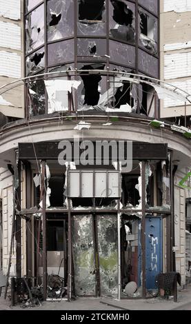 Supermercato distrutto. La facciata dell'edificio con buchi di proiettili e schegge. Guerra in Ucraina. Foto Stock