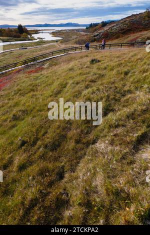 Islanda, Circolo d'Oro, Parco Nazionale di Thingvellir nei colori autunnali. Il Rift medio-Atlantico tra le placche tettoniche nordamericane ed eurasiatiche. La gola di Almannagja segna il bordo della placca tettonica nordamericana, con turisti turistici. Lago Thingvallavtn sul Reykjares Ridge nella Rift Valley Beyond. Foto Stock