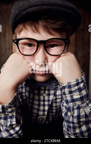 Ritratto, occhiali e ragazzo annoiato, triste espressione e pensiero alla depressione. Viso stanco, nerd e bambino piccolo in cappello, geek negli occhiali o esausto Foto Stock