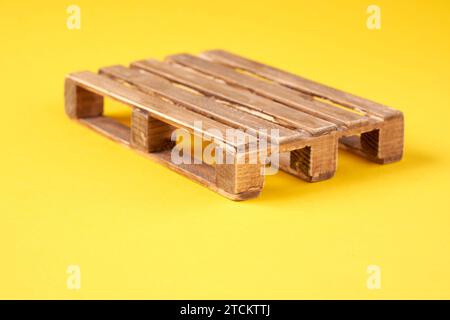 pallet miniaturizzati in legno su sfondo giallo Foto Stock