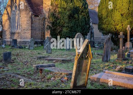 Tramonto in una gelida giornata invernale in un cimitero di Cardiff, Galles. Evocativo, triste, lutto, gotico, morte, aldilà. Concetti. Foto Stock