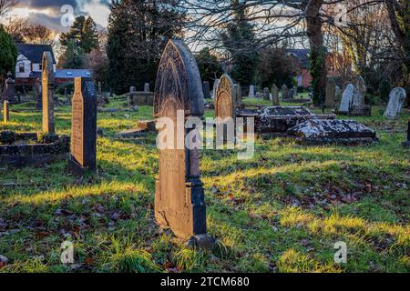 Tramonto in una gelida giornata invernale in un cimitero di Cardiff, Galles. Lapidi. Evocativo, triste, lutto, gotico, morte, aldilà. Concetti. Foto Stock