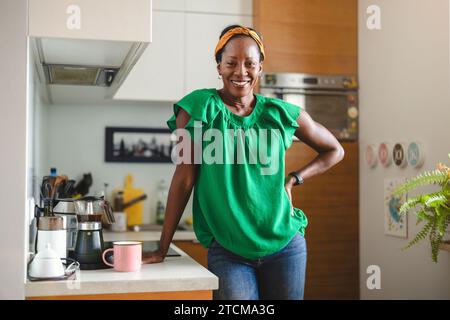 Ritratto di una donna matura sorridente in piedi nella sua cucina Foto Stock