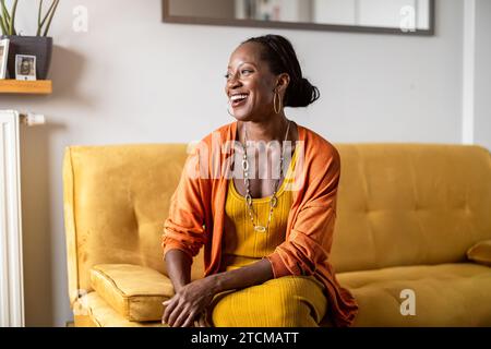 Ritratto di donna sorridente rilassante sul divano di casa Foto Stock