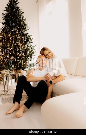Giovane donna incinta e suo marito festeggiano il Natale a casa e decorano l'albero di Natale. Foto Stock
