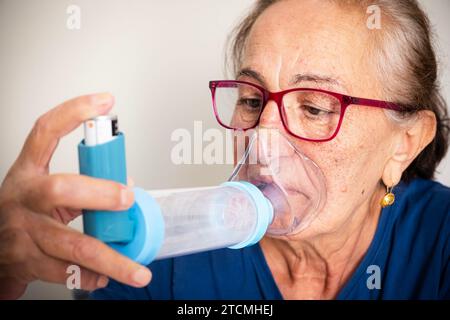 Donna anziana malata che fa inalazione con nebulizzatore. Donna asmatica che usa un inalatore. Foto Stock