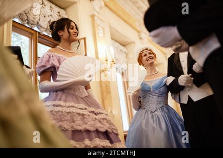 Vista dall'angolo basso in gruppo di signore e signori che chiacchierano nella sala da ballo Foto Stock