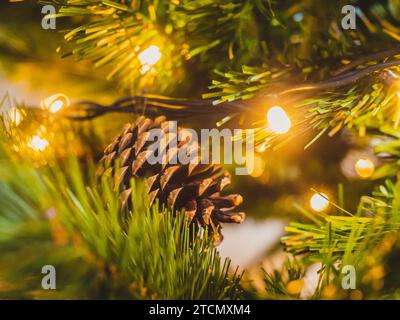 Un albero di Natale natalizio con più coni di pino illuminati da luci accese Foto Stock