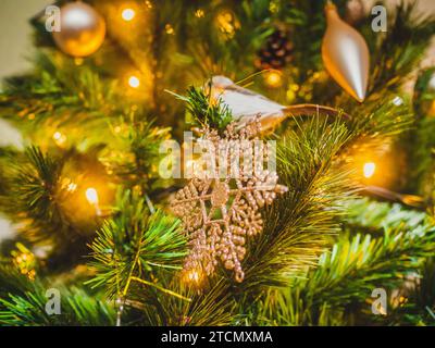 Un vivace ornamento natalizio rosso appeso a un lussureggiante albero di rami di pino Foto Stock