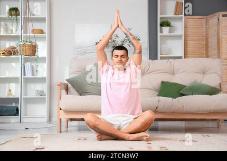 Un giovane che fa yoga sul tappeto a casa Foto Stock