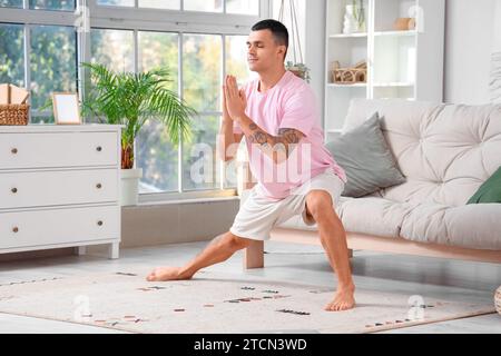 Un giovane che fa yoga sul tappeto a casa Foto Stock