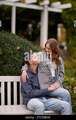 Romanticismo autunnale: Giovani coppie che si abbracciano e si baciano sulla panchina del parco. Giovani coppie che si baciano e si rallegrano al lago. adorabili giovani coppie che si baciano all'aperto Foto Stock