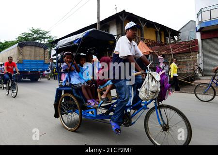 I bambini della scuola elementare malgascia vanno a scuola in risciò ciclistico a Moramanga, Madagascar. Foto Stock
