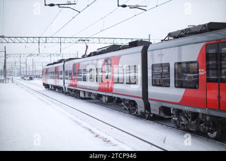 Un treno elettrico che parte dalla stazione in un giorno d'inverno Foto Stock