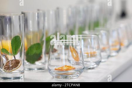 Pulire le tazze di vetro o i bicchieri da bere con fette di agrumi disidratate essiccate all'interno con foglie di menta pronte per un cocktail o un mocktail da versare Foto Stock