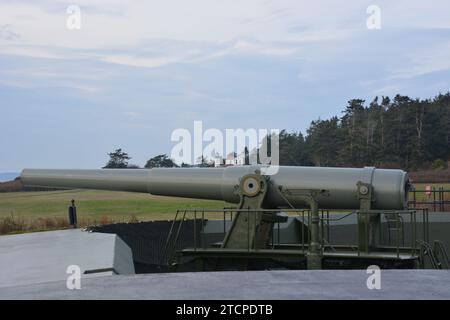 Grande canone militare a guardia del rettilineo di Juan de fuca a Fort Casey con il faro Admiralty Head. Foto Stock