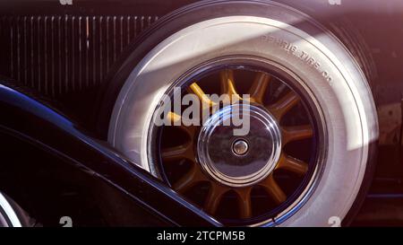 Vista ravvicinata di una ruota di scorta in legno a razze con pneumatici Whitewall di un'auto d'epoca Foto Stock