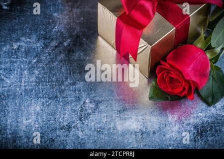 Confezione regalo con rose rosse su sfondo metallico graffiato Foto Stock