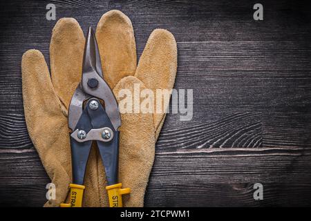 Tagliafili per guanti protettivi in pelle su pannelli di legno concetto di costruzione Foto Stock