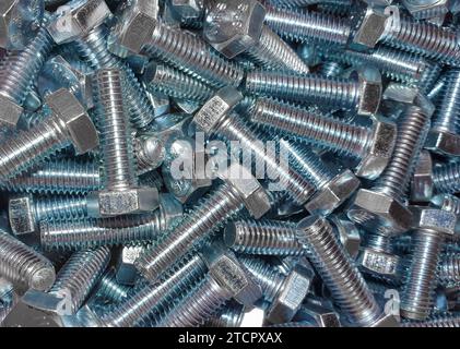 Un mucchio di viti metalliche su sfondo bianco, disposte in una pila Foto Stock