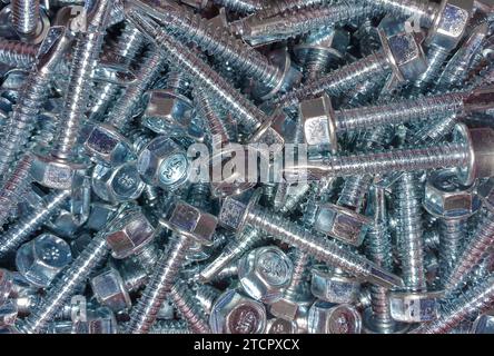 Una macro shot di un assortimento di viti e dadi sparsi su uno sfondo colorato Foto Stock