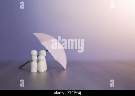 Ombrello e bambole in legno con spazio copia. Concetto di protezione della famiglia e copertura assicurativa. Foto Stock