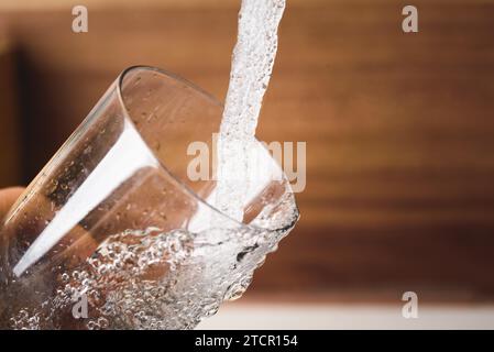 Riempimento di un bicchiere d'acqua dal rubinetto da cucina in acciaio inox. Concetto di acqua potabile. Austria acqua pura dalle montagne Foto Stock