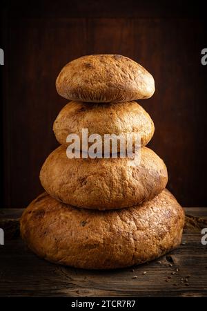 Quattro tipi di pane disposti in forma piramidale su fondo rustico di legno Foto Stock