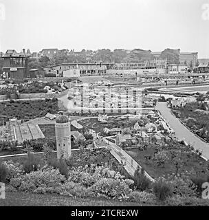 Madurodam, l'Aia, Paesi Bassi, fotografato nel 1955 – questo punto di vista mostra che i lavori di costruzione erano ancora in corso presso le strutture per i visitatori (sul retro). Madurodam è un parco a tema in miniatura, un villaggio modello e un'attrazione turistica nel distretto di Scheveningen dell'Aia. È sede di una gamma di repliche di modelli in scala 1:25 di famosi monumenti e stili di vita olandesi, città storiche, industria e sviluppi. Il parco è stato aperto nel 1952 e decine di milioni di visitatori hanno visitato l'attrazione con i profitti del parco diretti a varie organizzazioni benefiche nei Paesi Bassi. Foto Stock