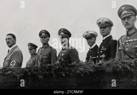 Nel giorno delle forze armate nel 1935, Adolf Hitler viene raffigurato con i suoi comandanti principali, mostrando la gerarchia della leadership militare nella Germania nazista. Da sinistra a destra: Generaloberst Hermann Göring, Comandante in Capo della Luftwaffe; Generalfeldmarschall Werner von Blomberg, Ministro della Guerra; Generaloberst Freiherr von Fritsch, Comandante in Capo dell'Esercito; Generaladmiral Dr. h.c. Erich Raeder, Comandante in Capo della Kriegsmarine. Questo raduno illustra il consolidamento del potere militare e dei diversi rami sotto il comando di Hitler. Foto Stock