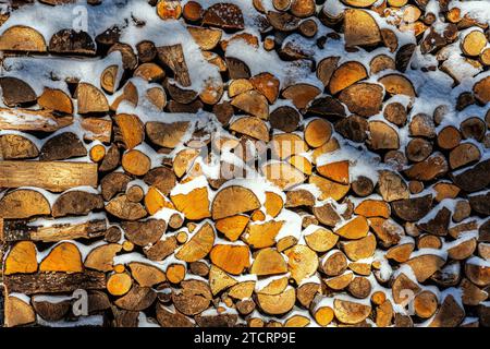 Tagliato a legna e pronto per il camino, impilato e coperto di neve. Abruzzo, Italia, Europa Foto Stock