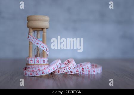 Immagine ravvicinata della clessidra e del metro a nastro. Spazio di copia per il testo. Dieta e concetto di perdita di peso. Foto Stock
