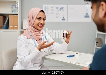 Ritratto di una donna islamica sorridente medico che mostra pillole Foto Stock