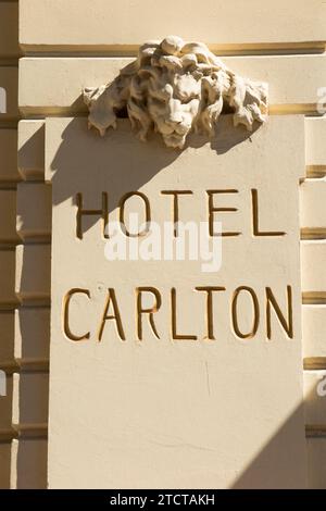 Il nome dell'Hotel Carlton / Carlton Cannes Hotel, Cannes, in stucco di cemento sul lato dell'edificio. Decorazione della testa di Leone sopra. (135) Foto Stock