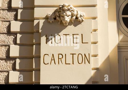 Il nome dell'Hotel Carlton / Carlton Cannes Hotel, Cannes, in stucco di cemento sul lato dell'edificio. Decorazione della testa di Leone sopra. (135) Foto Stock